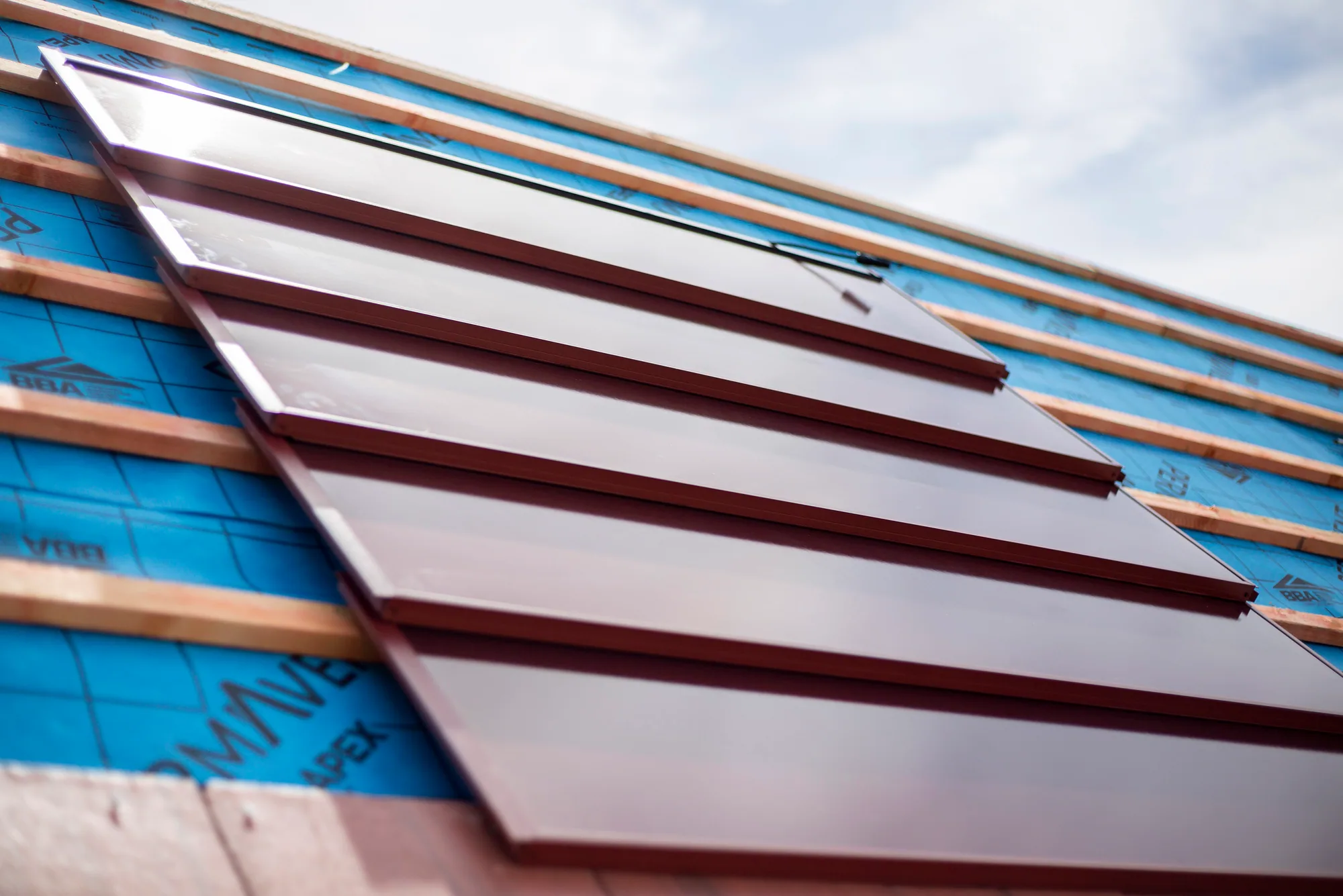 Close view of integrated red SolarTyle units aligned across timber battens