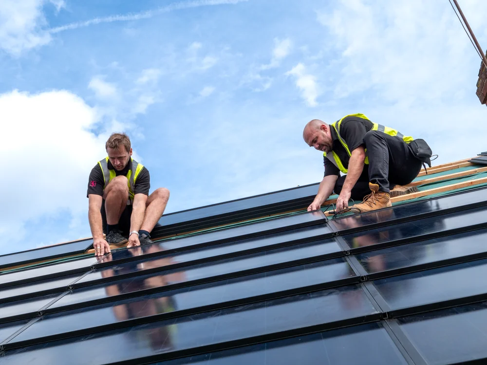 Installers positioning anthracite SolarTyle modules on the Anthony Drive roof